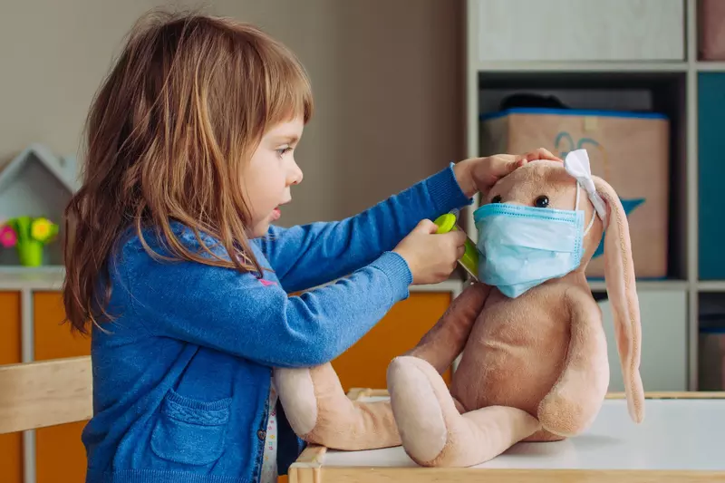 A child playing doctor with a stuffed animal. 
