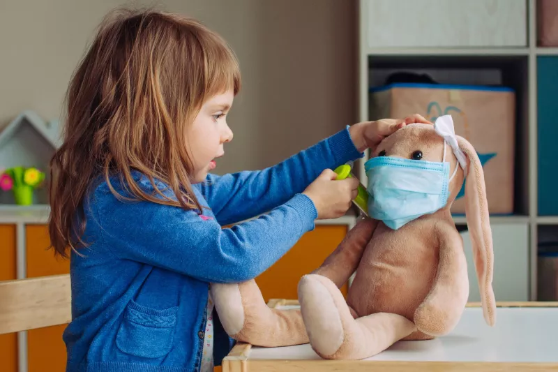 A child playing doctor with a stuffed animal.