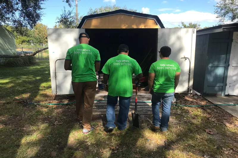 Three volunteers in front of a shed