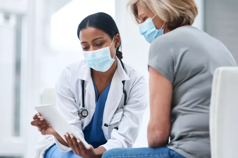 A physician showing something to her patient on her business tablet