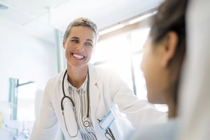 A doctor greets her patient at the bedside