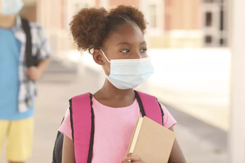 A girl attending school and wearing a mask.