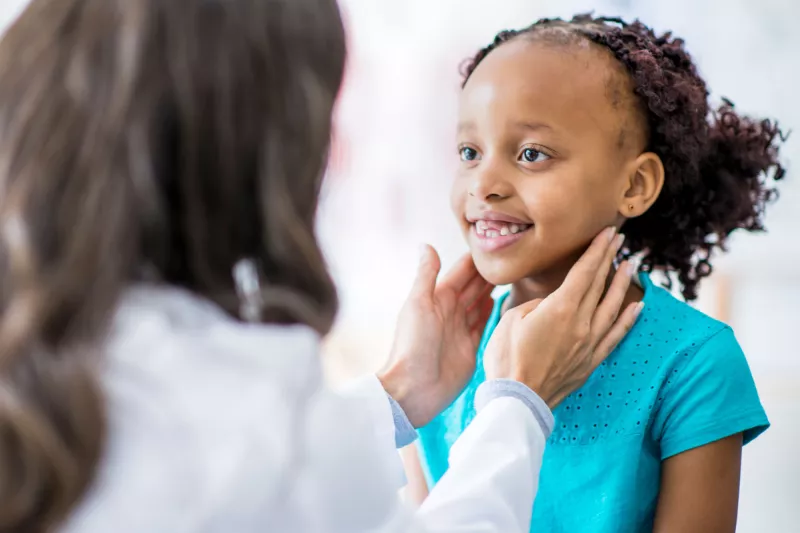 A girl has her throat checked at a doctor's appointment.