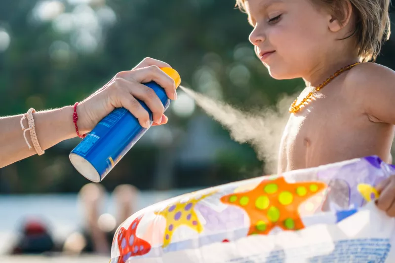 Little boy gets sunscreen protection from his mom at the beach