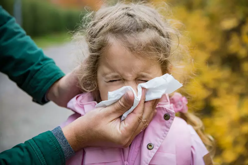 With the help of her mom, a little girl blows her nose