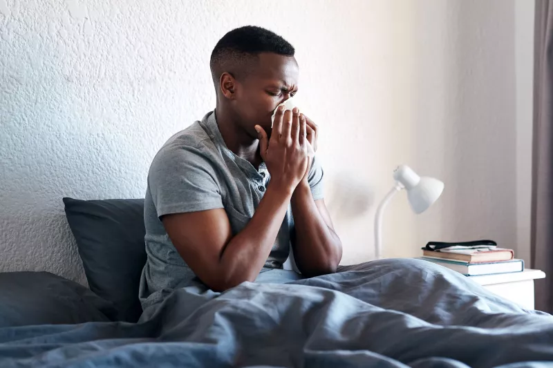 A man blowing his nose at home.