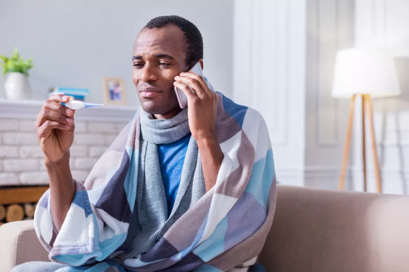 A man with a fever calling his doctor from home.