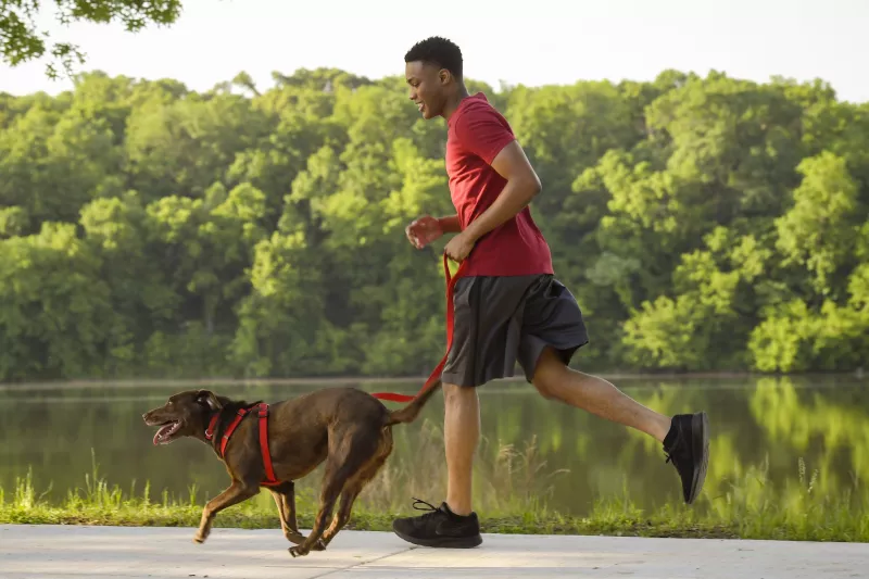 A man running outside with his dog.