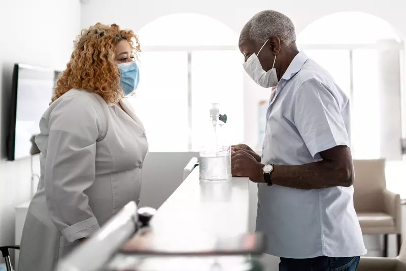 A man wearing a mask checking in for an appointment.