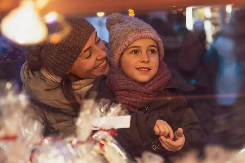 A mother and child looking at holiday storefronts. 
