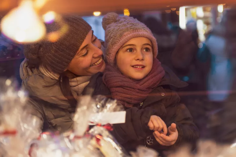 A mother and child looking at holiday storefronts.