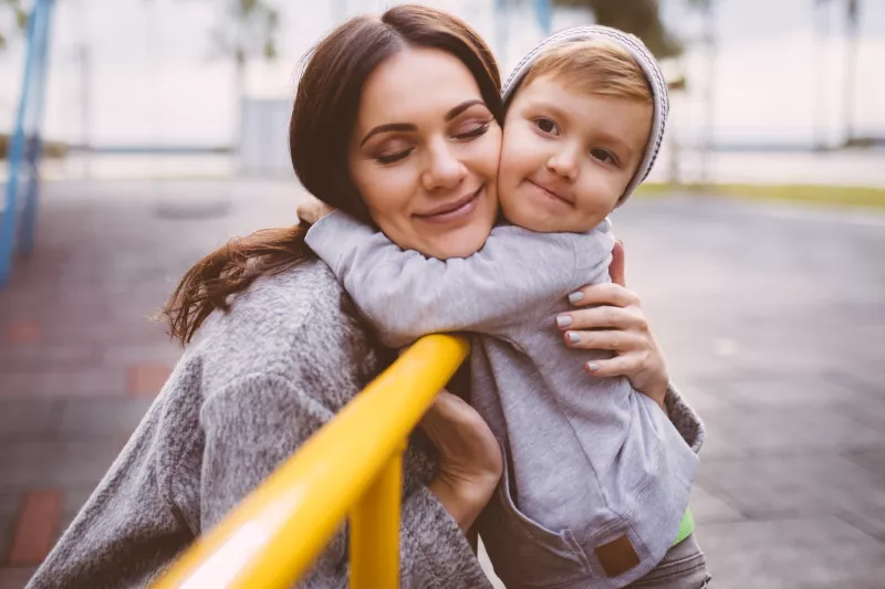 A mom hugs her son at the playground.
