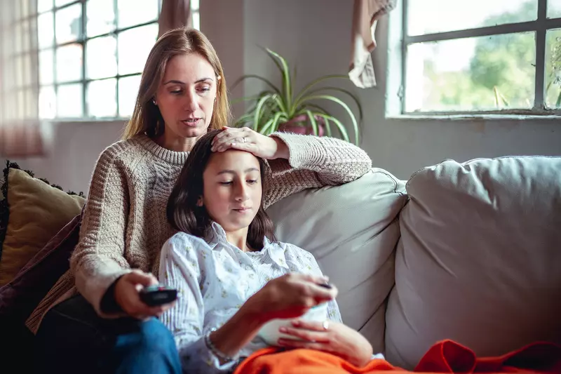 Hero Mom Comforts Her Sick Teenage Daughter on the Couch at Home.