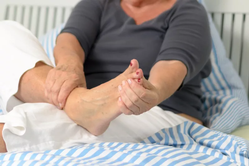 A senior woman massages her foot