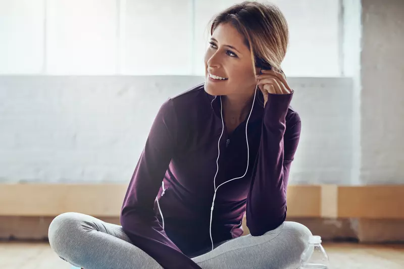 A woman wearing headphones and exercise clothes.