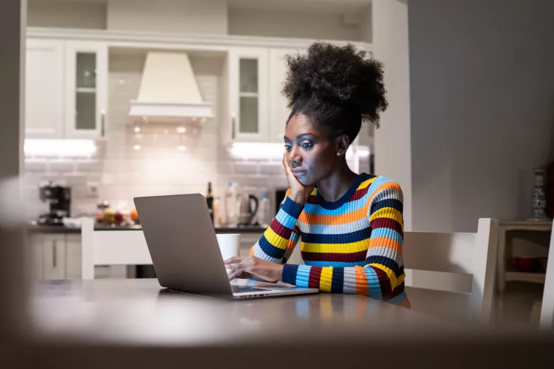 A woman in her living room and on her computer