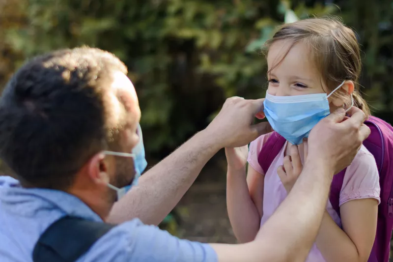 A dad helps his daughter get ready to go back to school.