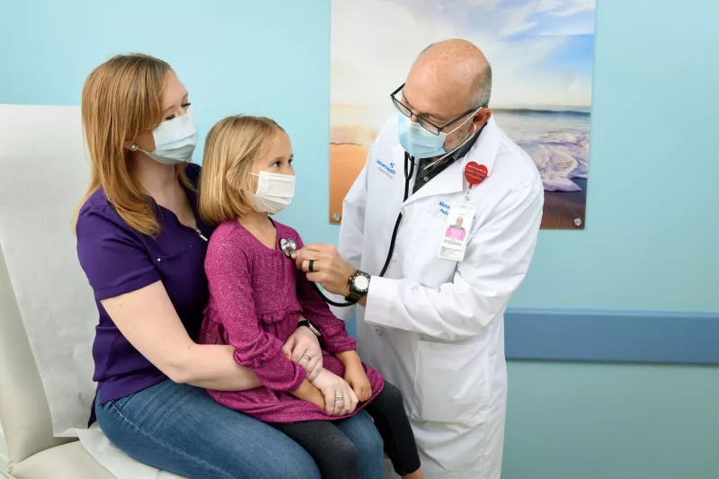 Doctor checking girl's heart beat