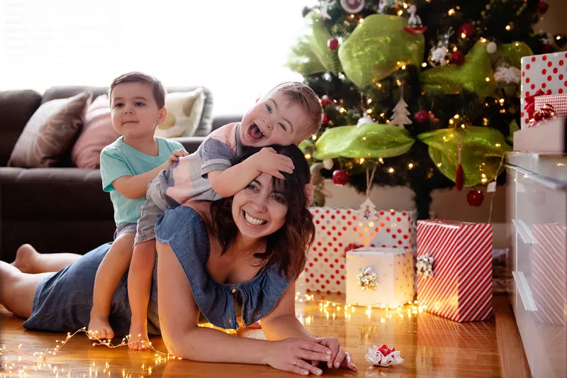 Caucasian mother with two sons laying under a Christmas tree