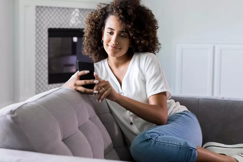 A woman on her cell phone at home on her couch. 