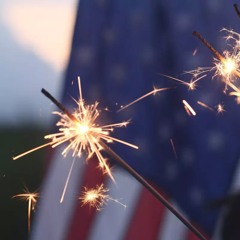 3 Sparklers Burn in Front of The American Flag