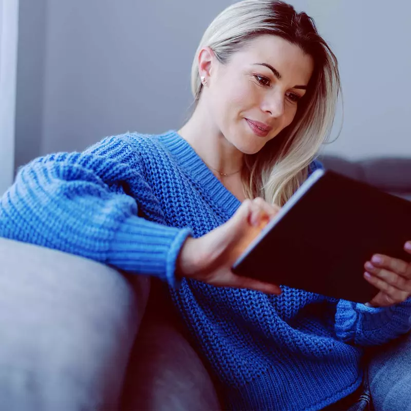 A woman on her couch and using her tablet