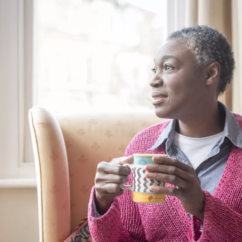 Enjoying her morning coffee, a mature woman reflects on life.