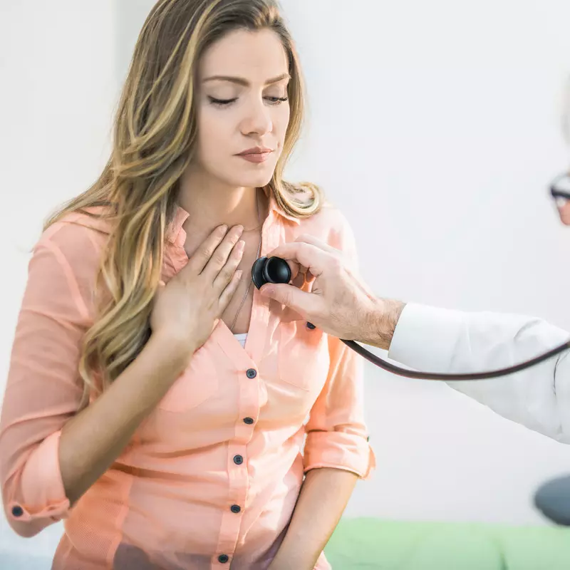 A doctor checking a woman's heart beat