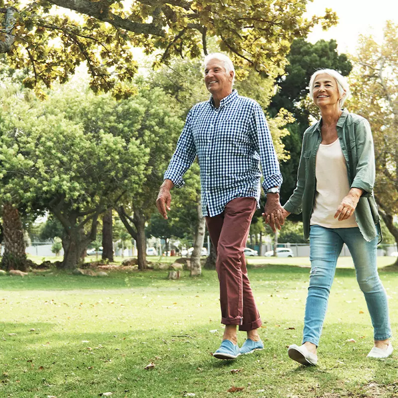 A mature couple walks in the park.