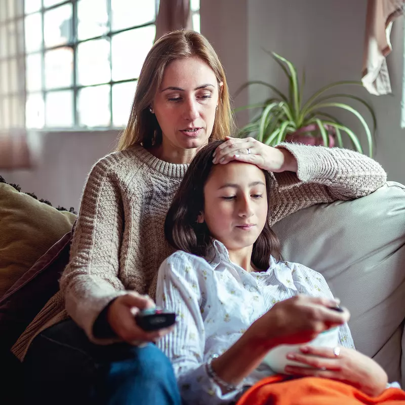 Hero Mom Comforts Her Sick Teenage Daughter on the Couch at Home.
