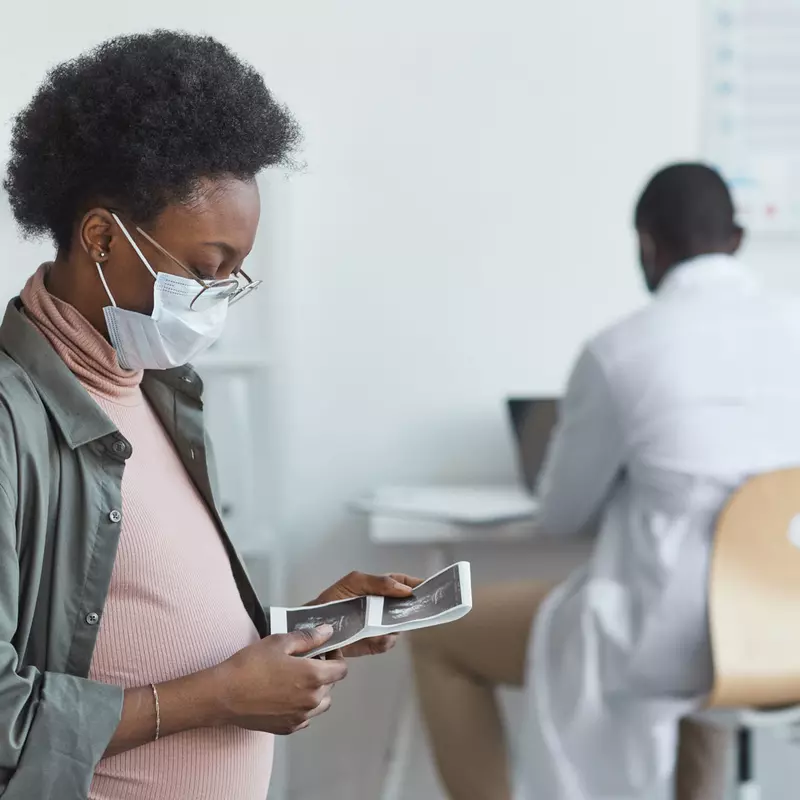 A pregnant woman looking at lab results in her doctor's office
