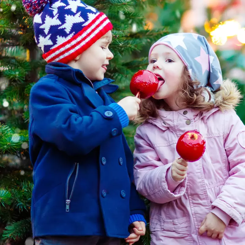 Two children at candy apples near the holidays.