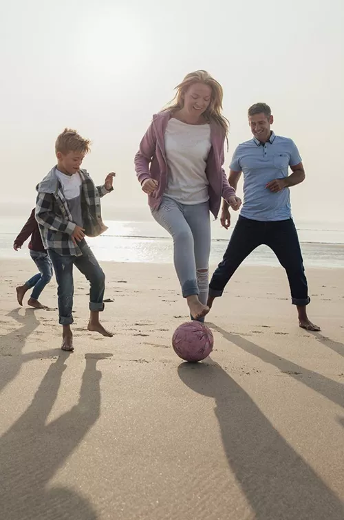 A family plays a friendly game of soccer on the beach