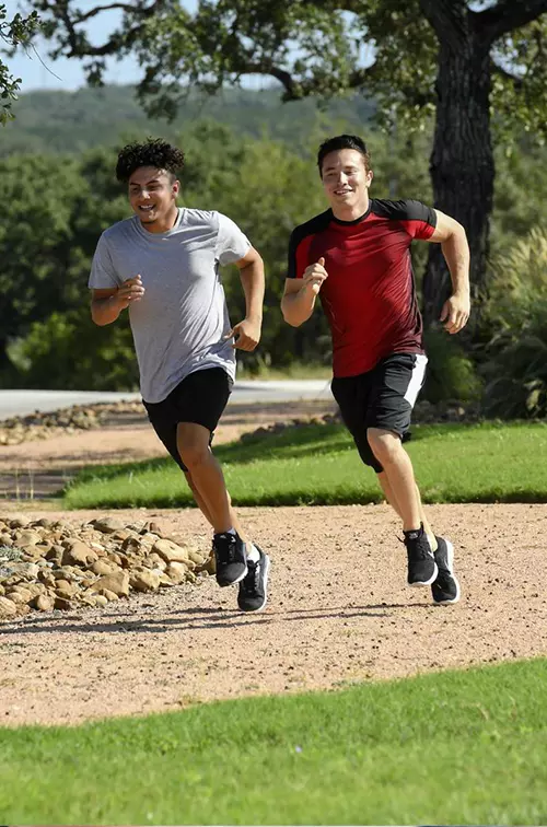 Two young men running outside on a path.