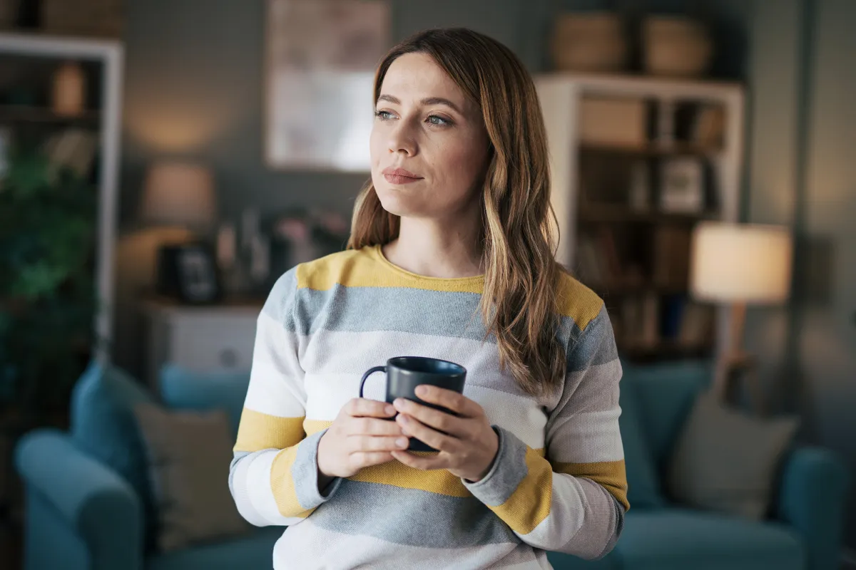 Woman holding a cup of coffee in her living room